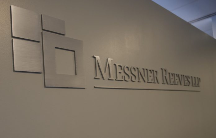 LogoFinal A silver brushed chrome logo that reads Messner Reeves on a white wall.