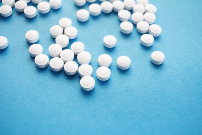 A group of small white pills on a blue background.