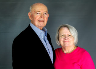 Jury Verdict Reporter of Colorado Celebrates 40th Anniversary A man wearing a suit coat and a woman wearing a pink top pose for a picture with a gray background.