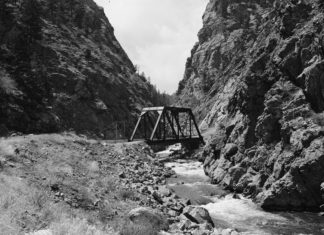 The 100-Year-Old South Platte River Compact a black and white photo shows a bridge overlooking a river with steep looking mountains on either side