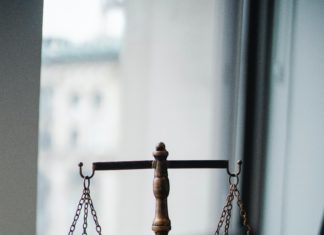 Colorado’s Korey Wise Innocence Project Continues Work Helping Those in Need Two scales are attached by chains to upper hooks that are supported by a small column. It is the “scales of justice.” In the foreground a gavel can be seen.