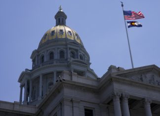 House of Representatives Members Accused of Violating Sunshine Law in Lawsuit The Colorado Capitol Building. A close up image of an official building with a gold dome over a rotunda with pillars. On the right of the dome is a flag pole with the American flag above the Colorado flag.