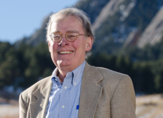 Remembering Charles Wilkinson, Longtime ‘Law of the West’ Professor An older man with white hair and glasses wearing a checkered blazer and a blue button-up shirt smiles outside with the mountains in the background.