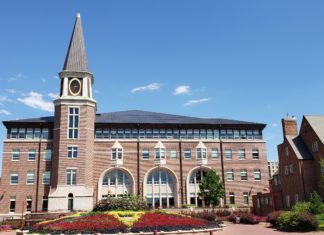 Yegge Scholars Continue Legacy More than 50 Years Later A large building with a pointed tower. In front of it are many flowers that are arranged. There are also buildings on the sides of the building in the center.