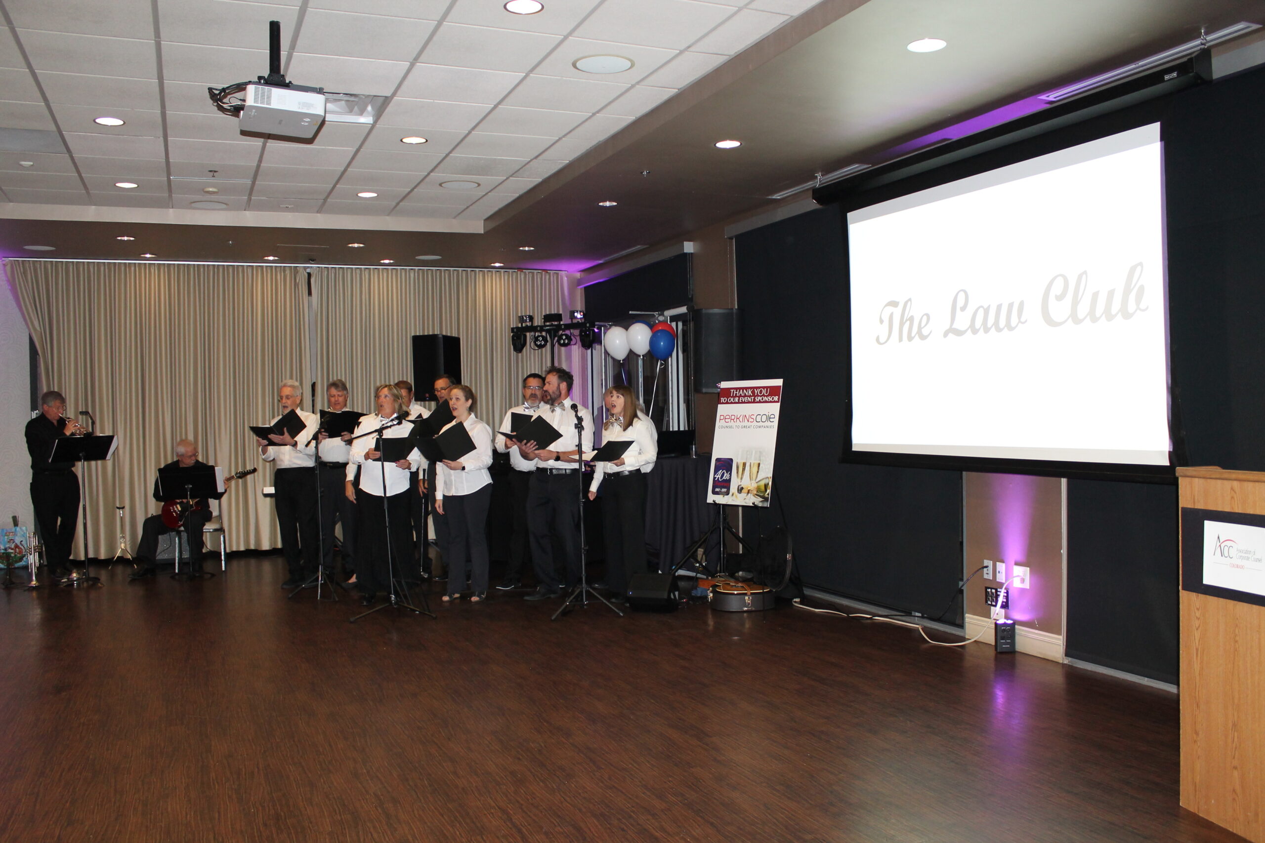 The Law Club musical group is performing next to a screen that says "The Law Club."