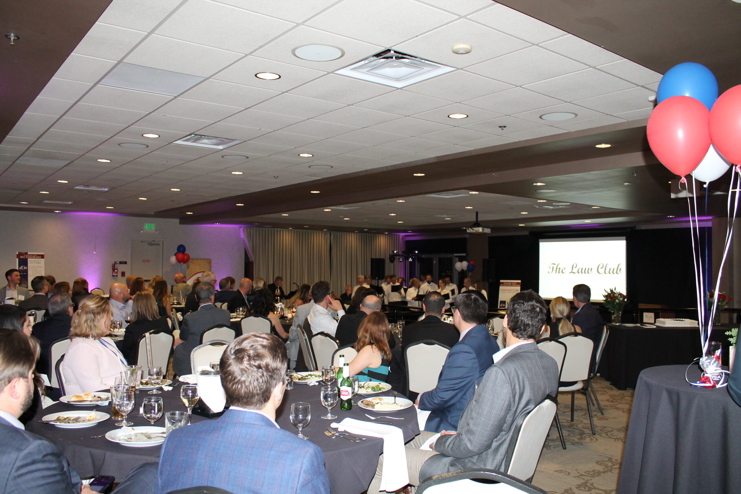 A crowded room full of people at tables watches a musical performance