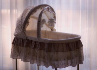 Experts Weigh in on Colorado Surrogacy Law A crib with a curtain behind it. Some stuffed animals are hanging above it.