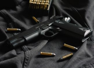 Expert Advice: New Colorado Gun Laws A black firearm has golden colored bullets surrounding it as it all lays on a black surface.