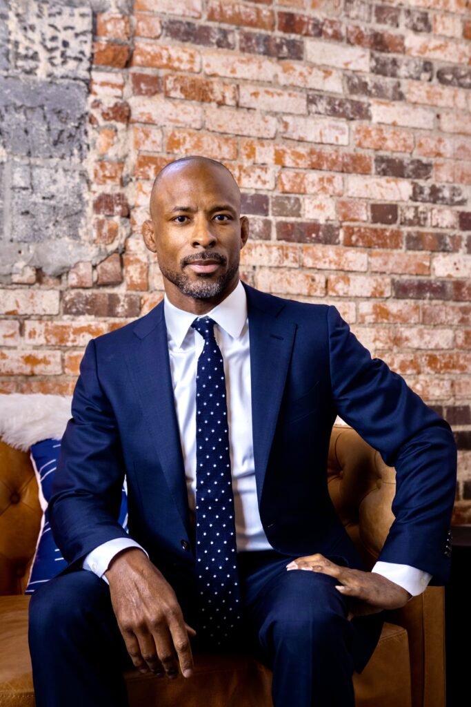 2024 Top Litigator Tyrone Glover sitting on a chair in front of a brick wall. 