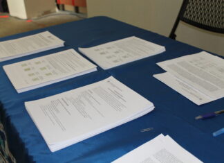 E-Verify+ Coming Soon But Employers May Hesitate to Use the New System a table with stacks of forms, a couple of pens and a paperclip.