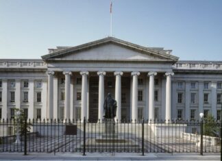 Attorneys Discuss the Corporate Transparency Act as Filing Deadline Approaches A view of the front of the U.S. Department of Treasury Building in Washington D.C. A short fence sits in the foreground in front of a statute. The building is white, with columns and a classical architectural style.
