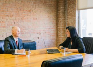 The Difficulties, Draws of Law Firm Mergers Two working professionals smile at each other in a meeting room.
