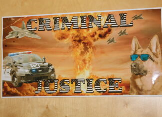 Colorado High School Kids are Learning More About Civic, Legal Literacy at Warren Tech On a sign, an eagle and a dog sit side-by-side in a police car with sunglasses on. A fiery explosion dominates the background and fighter jets dot the sky. The dog in the car wearing sunglasses is also in the foreground, looking straight ahead. The sign says “criminal justice”
