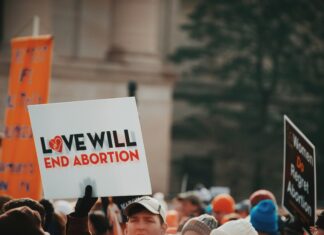 The Colorado Law at the Heart of Health Care Clinic “Bubble Zones” Across the Country An anti-abortion protest, with a sign saying “Love will end abortion” in focus.